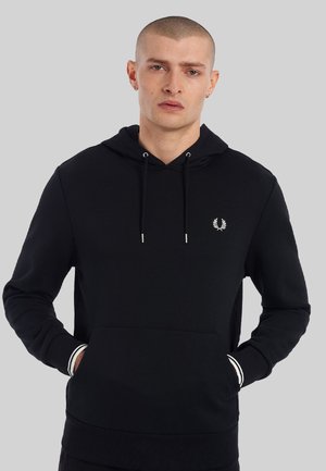 Schwarzer Kapuzenpullover mit Fronttasche, elastischen Bündchen und weißen Streifenakzenten. Enthält ein kleines gesticktes Logo auf der Brust.