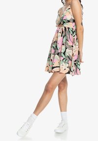 Robe à imprimé floral avec un décolleté en V profond, un devant noué et une jupe évasée. Le tissu présente des couleurs pastel sur un fond noir.