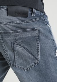 Tmavě modré džíny z denimu s unikátním vzorem na zadní kapse, černou koženou značkovou nášivkou a jemným vyblednutím na látce.