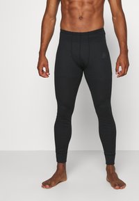 Musta leggins, jotka on valmistettu tiukasta joustavasta materiaalista, jossa on sileä pinta, ommellut saumat ja nilkkasaumat. Ei näkyviä brändimerkintöjä.