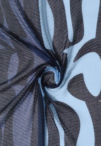 Tissu bleu clair torsadé au centre avec de grandes formes abstraites gris foncé et un voile transparent bleu marine foncé.