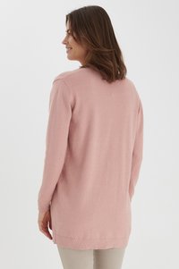 Maglione rosa a maniche lunghe, realizzato in morbido tessuto a maglia con una vestibilità comoda. Presenta polsini a coste e fessure laterali per facilitare il movimento.