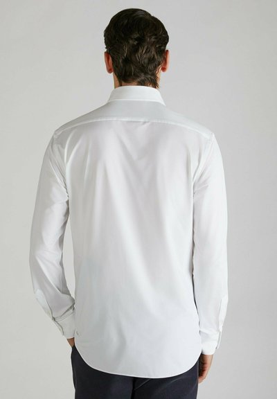 Camicia bianca a maniche lunghe con una texture liscia, colletto classico e polsini abbottonati, con orlo curvo e design minimalista.