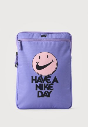 Μωβ τσαντάκι Nike με εμπρός φερμουάρ, που διαθέτει ένα ροζ χαμογελαστό πρόσωπο με μαύρο λογότυπο Nike swoosh ως στόμα και το κείμενο "Have a Nike Day."