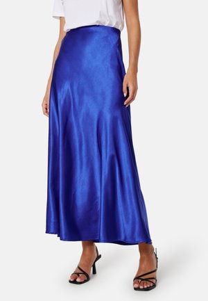 Gonna maxi di satin in un blu vivace, con una superficie liscia e un design svasato, abbinata a sandali neri con cinturini.