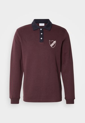 Burgundy long-sleeve polo with navy collar, three buttons, and embroidered shield logo on the left chest. Soft fabric and ribbed cuffs.