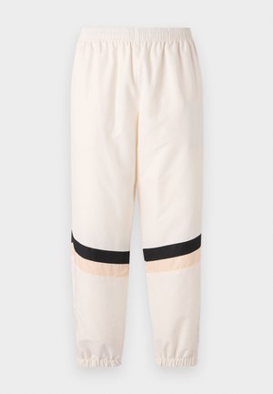 Cream-colored track pants with an elastic waistband. Features black and peach horizontal stripes at the lower legs and elastic cuffs.