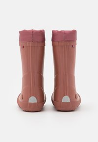 Roze waterdichte rubberlaarzen met een zachte stoffen boord, ronde neus, gekartelde zool en reflecterende accenten op de hak en zijkanten.