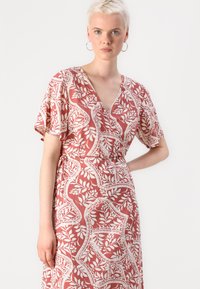 Red floral wrap dress with short flutter sleeves, featuring a v-neckline and white leaf patterns, tied at the waist for a fitted look.