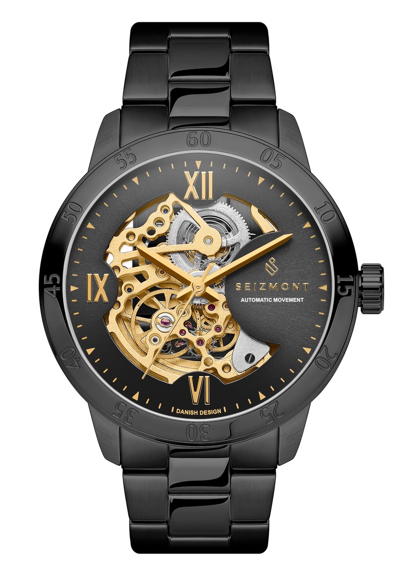 Automatisk klokke med svart metallarmbånd og -hus, gull- og sølvfarget mekanisk bevegelse synlig, svart urskive med gulldetaljer og markeringer.