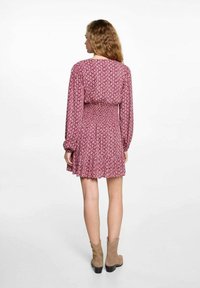 Raspberry-colored dress with long sleeves, smocked waist, and flared skirt. Features a floral pattern and soft fabric texture.