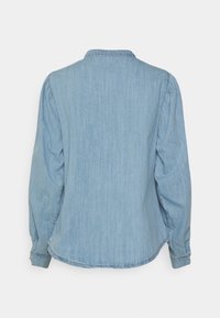 Ljusblå denimskjorta med avslappnad passform, långa ärmar och ryggsömn. Har subtila vertikala ränder och rundad nederkant.