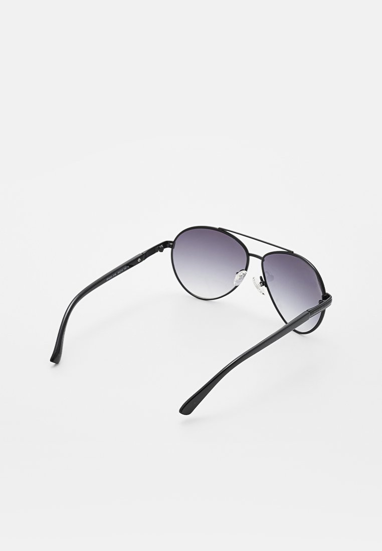 Occhiali da sole aviator neri con lenti sfumate, montatura in metallo sottile e naselli regolabili. Braccia lunghe e sottili che si assottigliano verso le estremità.