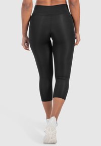 Leggings capri neri realizzati in tessuto elastico, dotati di una vita alta e di una finitura liscia e opaca. Si abbinano bene a calzature sportive.