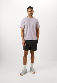 Light purple cotton t-shirt with short sleeves, horizontal seam detail across chest, paired with black shorts and gray sneakers.