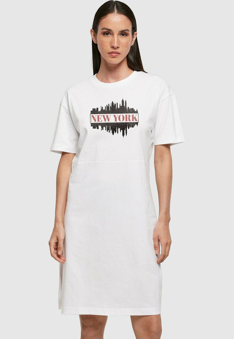 Hvid bomulds t-shirt kjole med trykt New York skyline grafik i sort, med rød tekst. Korte ærmer og afslappet fit design.