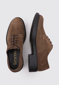 Zapatos de ante marrón con cordones, con una suela de goma negra resistente, que presentan una puntera redondeada y sutiles acentos de costura.