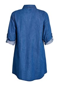 Denimskjorta med krage och uppvikta ärmar, med en lös passform och rundad nederkant, som visar en strukturerad blå tyg.