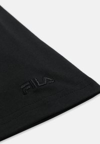 Coin de manchette en tissu noir avec logo FILA brodé en noir et couture visible sur fond blanc.