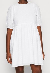 Vestido blanco de mangas abullonadas hecho de una tela ligera, con un patrón de puntos texturizados y un corte holgado con una cintura fruncida.