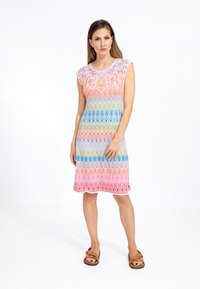 Abito senza maniche fino al ginocchio con un motivo a zigzag colorato nei toni del rosa, blu e giallo, con orlo ondulato.