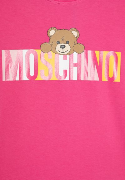 Camiseta de algodón rosa con una ilustración de un oso y el texto "MOSCHINO" en letras gruesas y coloridas. Textura suave, escote de cuello redondo.