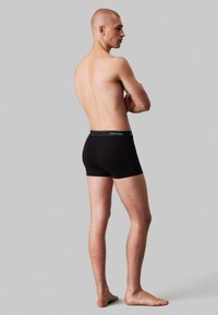 Zwarte katoenboxershorts met een logo-op de tailleband, met een fitted design en een gladde textuur. Zicht van opzij met een minimale achtergrond.