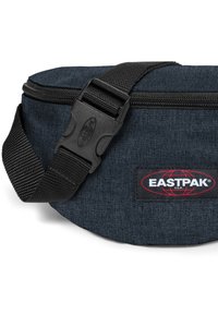 Svart denim Eastpak midjeväska med dragkedjestängning, justerbar rem och märkespatch med en globlogotyp i rött. Slät textur.