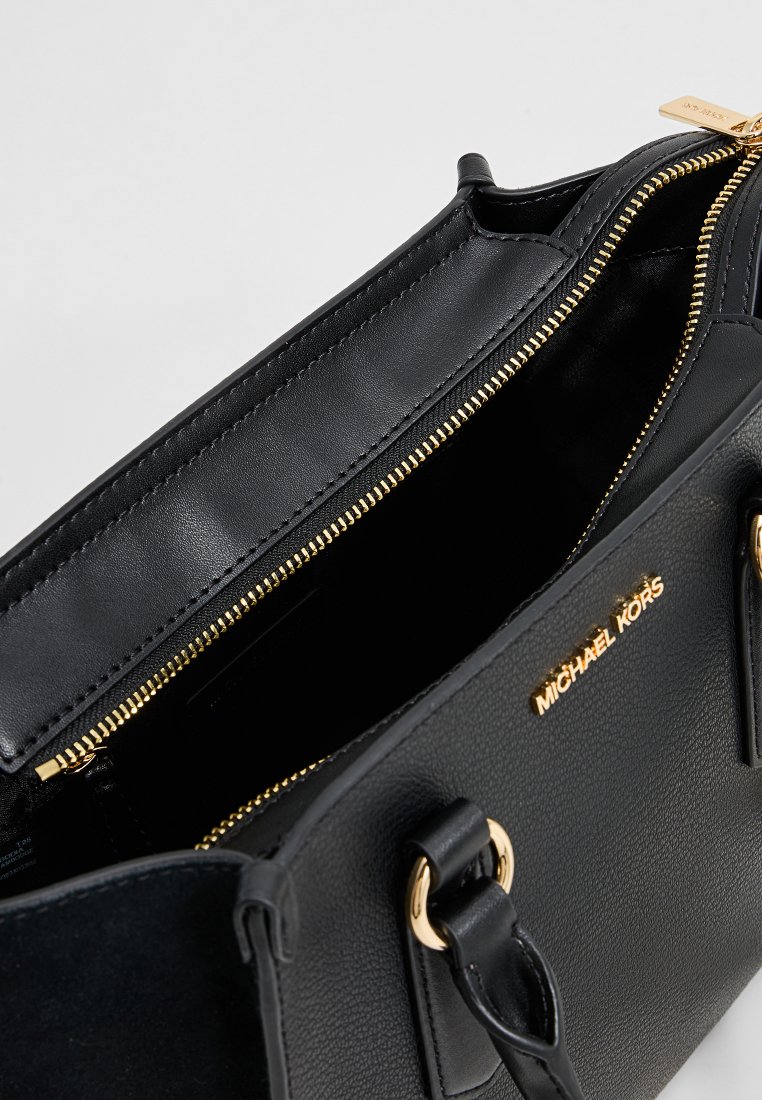 Borsa in pelle nera Michael Kors con zip dorata parzialmente aperta, che mostra un ampio interno e dettagli in oro sulle maniglie.