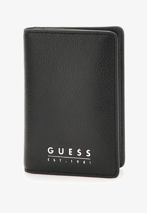 Portafoglio in pelle nera con superficie testurizzata, bordi cuciti e logo in rilievo con "GUESS EST. 1981" sul davanti.
