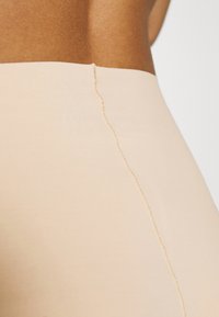 Beiga söml�ösa leggings med en slät textur, hög midja och subtil upphöjd sömnad längs sid sömmen och fållen.