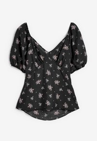Blouse noire à manches courtes bouffantes, col en V, avec un petit imprimé floral rose et blanc dispersé sur le tissu.