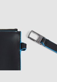 Bolsa de cuero negro con acentos azules, que cuenta con un cierre de cremallera y un cierre de metal plateado. Textura lisa con detalle de costura visible.