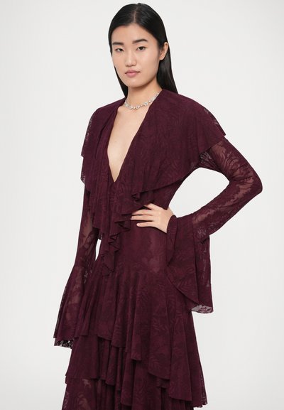Abito a strati color bordeaux con maniche arricciate e scollo a V profondo. Realizzato in pizzo strutturato, presenta motivi floreali e gonna svasata.