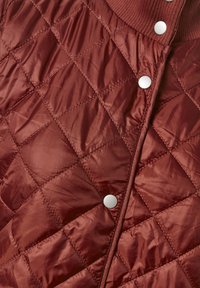 Kurtka pikowana w kolorze burgundowym, wykonana z gładkiego, błyszczącego materiału, z pr�ążkowanym kołnierzem i srebrnymi zapięciami na napy z przodu.