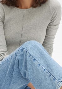 Gray ribbed long-sleeve top paired with light blue denim jeans. The top features a round neckline and fitted sleeves, while the jeans have a relaxed fit.