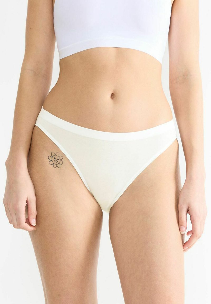 Weiße Baumwollbikinislips mit einem kontrastierenden Bund, die ein niedriger Schnitt und eine glatte Textur aufweisen.