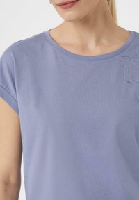 Lavendelfarbenes T-Shirt mit kurzen Ärmeln, Rundhalsausschnitt und einem bestickten Blumenmuster in kontrastierender Farbe auf der Brust.