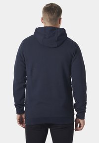 Sudadera con capucha azul marino hecha de una tela suave, con un diseño sencillo, mangas largas y un bolsillo tipo canguro. Vista posterior mostrada.