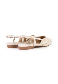 Sandalias de tejido beige con suela plana marrón y correa de tobillo ajustable. Presentan un upper texturizado con un diseño de perforaciones.