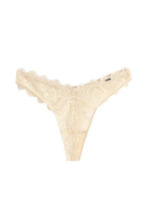 Kremfarvet blonderstrings med blomstertryk og bølget kant på en hvid baggrund.