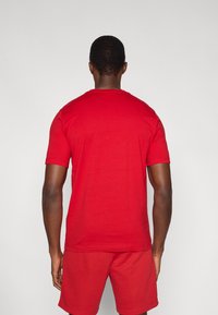 Κόκκινο κοντομάνικο μπλουζάκι από απαλό βαμβακερό μείγμα, με στρογγυλή λαιμόκοψη και άνετη εφαρμογή, συνδυασμένο με αντίστοιχα κόκκινα σορτς.