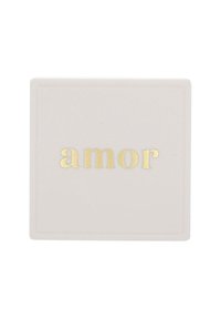 Vit kvadratisk platta med gyllene präglat ord "amor" centrerat på ytan.