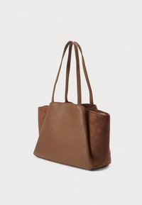 Barna táska sima bőrből készült elülső résszel és puha gyapjú oldalrészekkel, két hosszú fogantyúval és tágas, téglalap alakú formával.