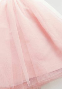 Soft pink layered tulle fabric with fine mesh texture forming gentle folds on a flat surface.