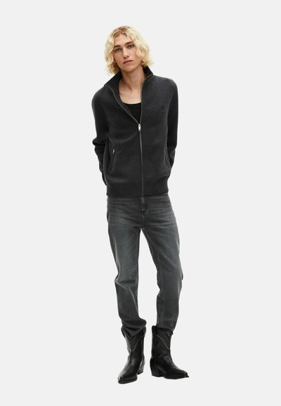 Czarny szary sweter na zamek z wysokim kołnierzem, w zestawieniu z szarymi dżinsami i czarnymi kowbojskimi butami, tworząc nowoczesny, Casualowy look.