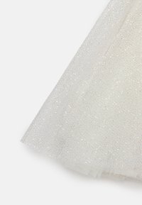 Genomskinligt vitt tyg med en glittrig textur, som har en subtil lyster och en delikat vävning. Kanterna har en mjuk, rå finish.