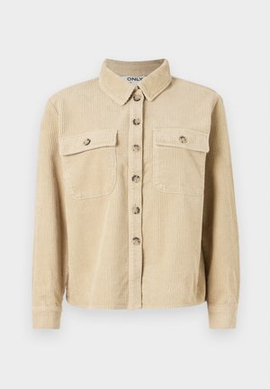 Chemise en velours côtelé beige avec un col, deux poches avant et une fermeture à boutons. Présente une texture côtelée verticale et des manches longues.