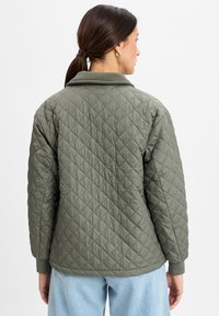 Gevoerde olijfgroene jas met kraag, geribde manchetten en een getextureerd ruitpatroon, met een ontspannen pasvorm en zachte stof.