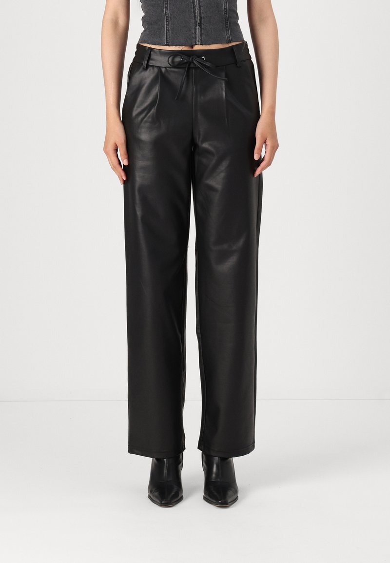 Des pantalons large en simili cuir noir présentent une taille cintrée avec un cordon de serrage et des plis à l'avant, offrant une texture lisse et brillante.